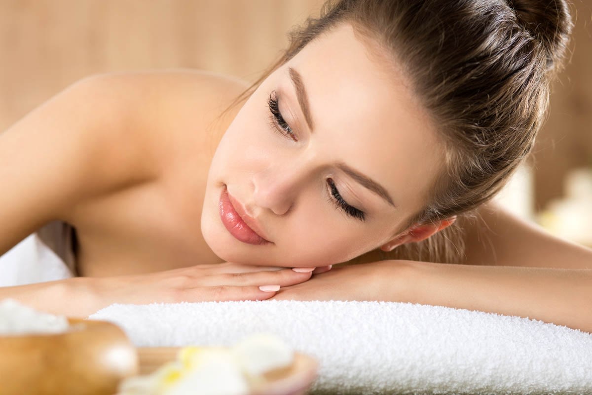 Beautiful young woman laying at spa salon