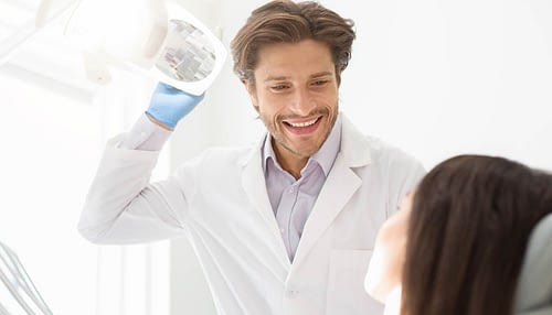 Cheerful young dentist greeting his female patient