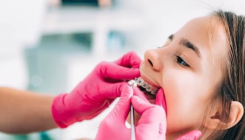 Orthodontist checking girl’s dental braces