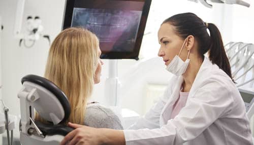 Dentist talking to worried woman during dental checkup