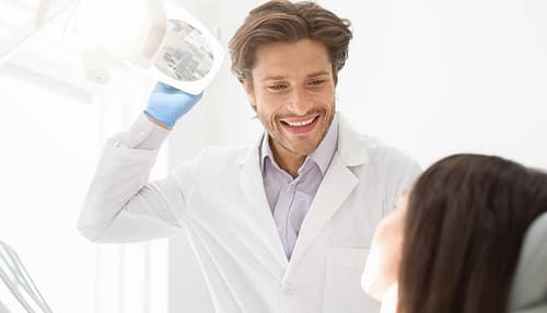 Cheerful young dentist greeting his female patient