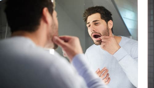 Young man checking tooth in bathroom