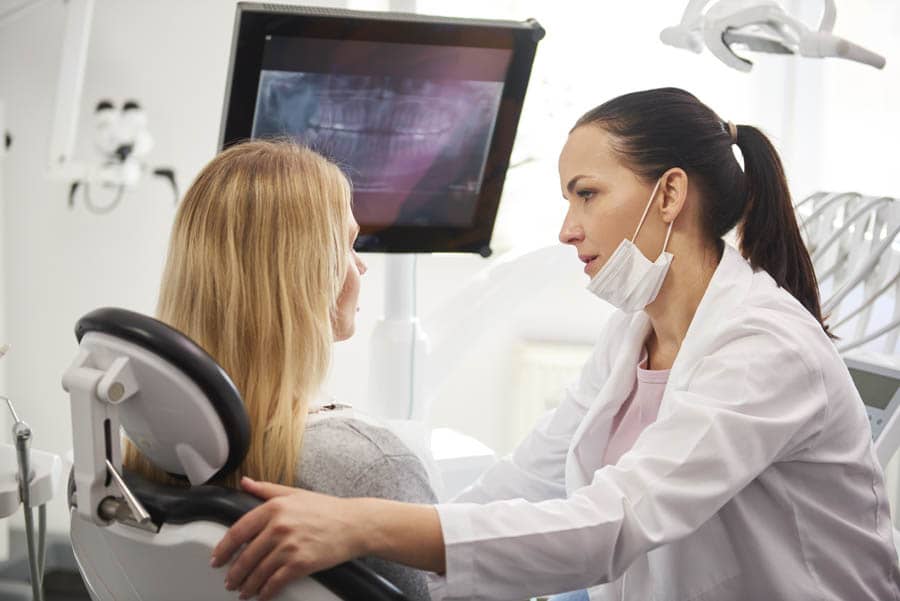 Dentist talking to worried woman during dental checkup